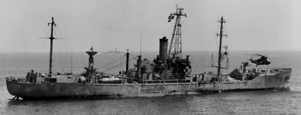 U.S.S. Liberty listing to starboard from hull damage, as a helicopter airlifts wounded from its foredeck. (U.S. Navy)